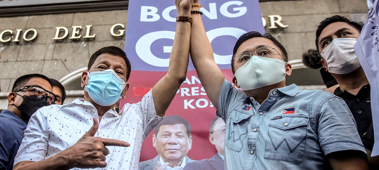Philippine President Rodrigo Duterte (L) raises the hand of senator Christopher 'Bong' Go after he filed his candidacy for president in the 2022 elections before the November 15 deadline at the Commission on Election in Manila on November 13, 2021. (Photo by JAM STA ROSA / AFP)